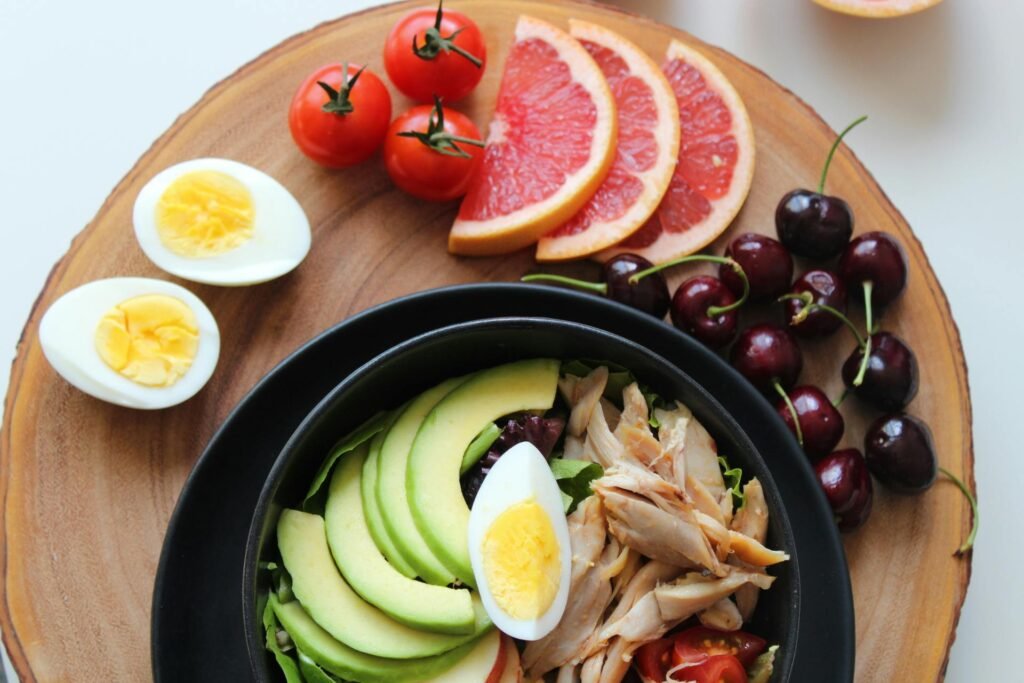 pexels-photo-793759-793759 A vibrant, healthy salad bowl with avocado, eggs, tomatoes, grapefruit, and cherries on a wooden board.
